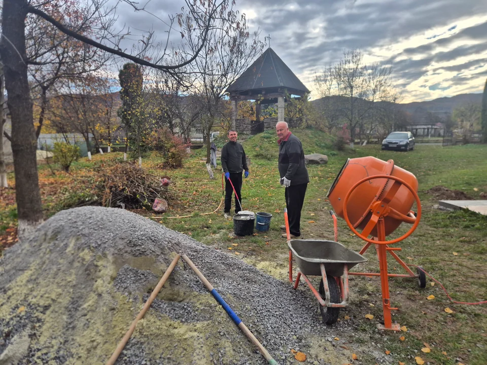 The parish pastor and a helper working on the parish grounds beside a concrete mixer